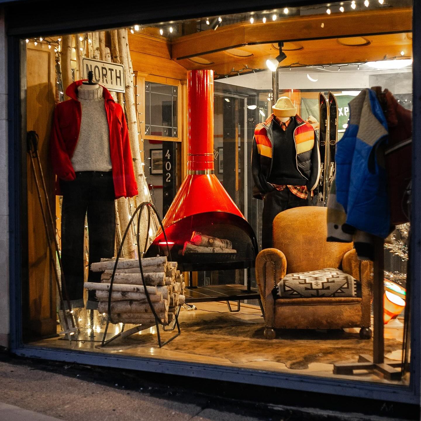 A window display with clothing and a fireplace.