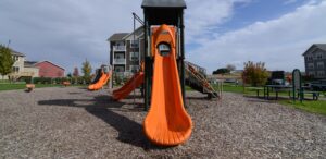a playground with an orange slide and a black roof