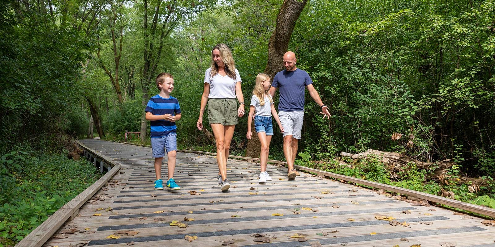 a family walking down a wooden path in the woods