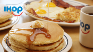 a stack of pancakes with syrup and eggs on a table